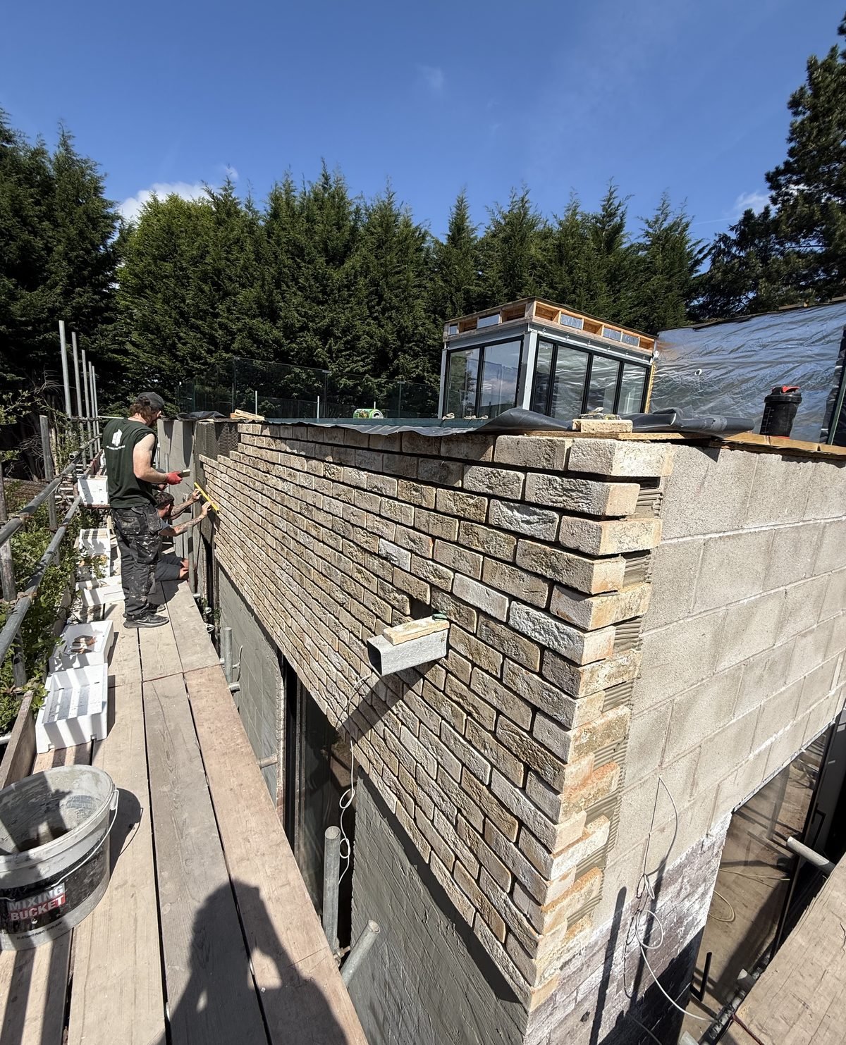 Buff brick slips being fitted to an exterior wall from the scaffold