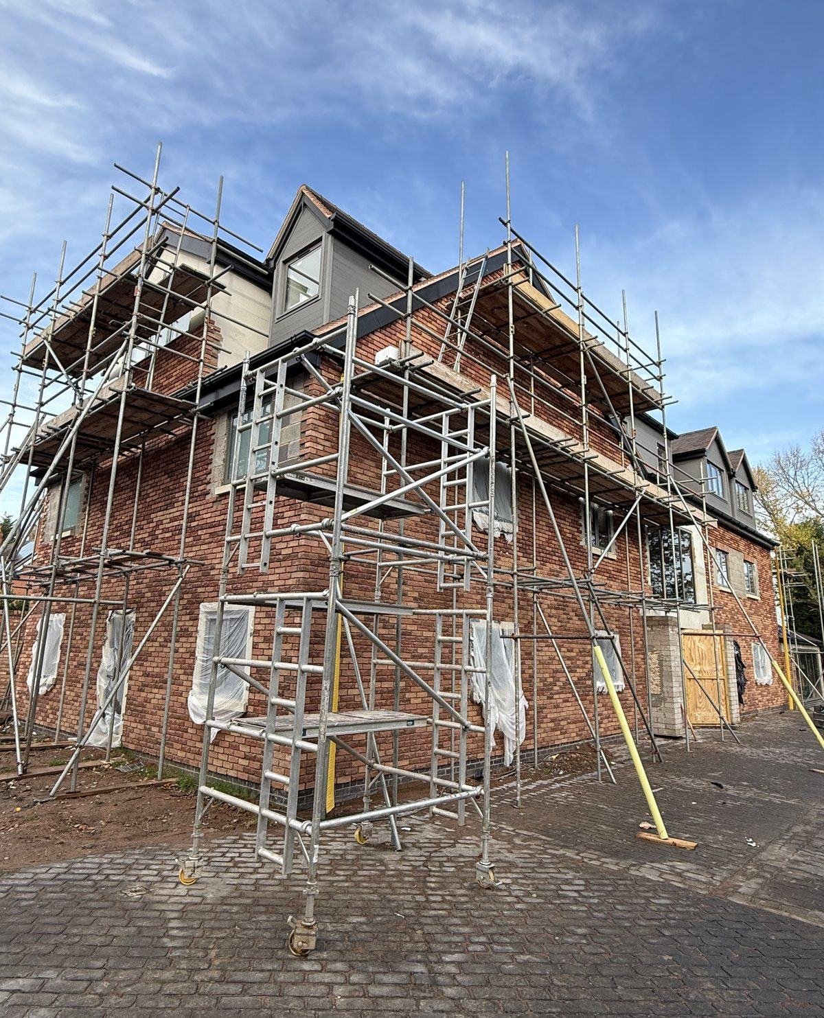 The new-build under scaffold, mostly clad in red brick slip