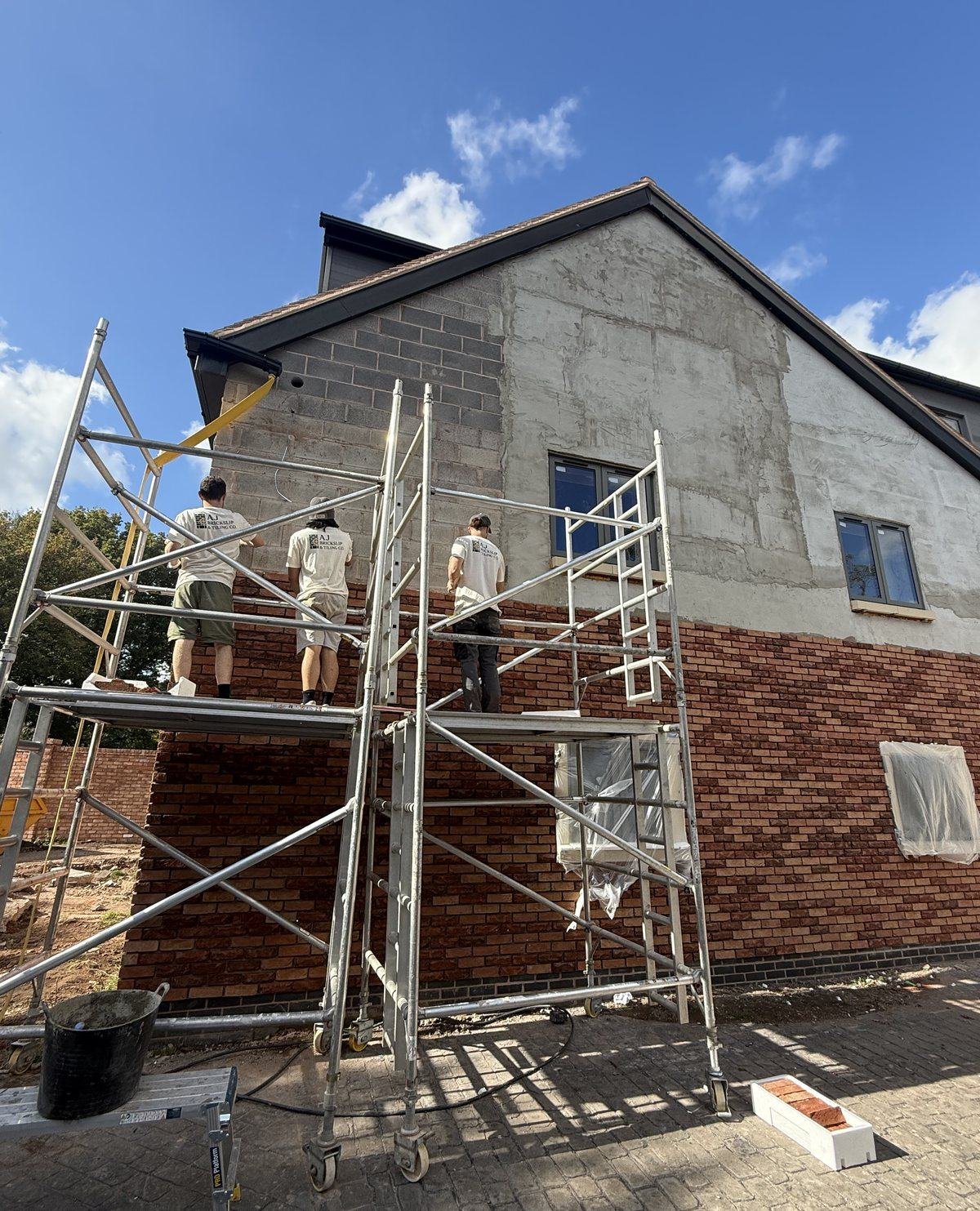 Red brick slips being fitted to the gable from scaffold towers