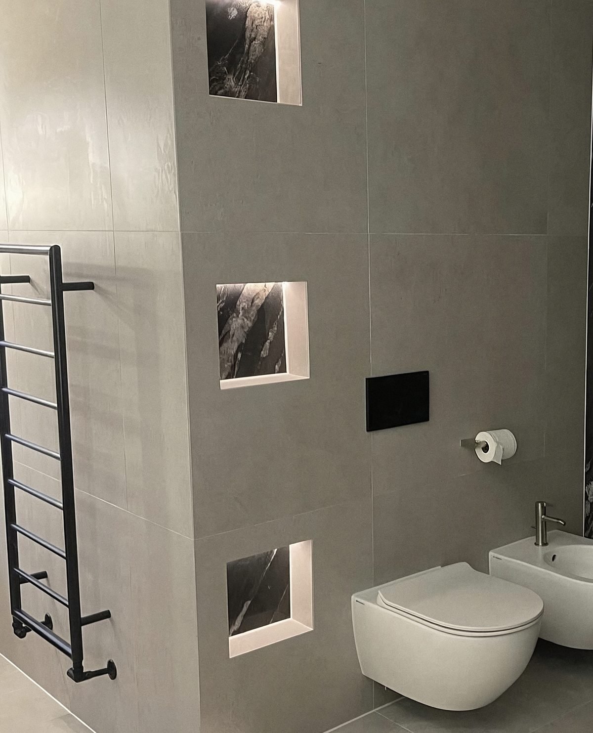Large-format grey porcelain wall with backlit niches