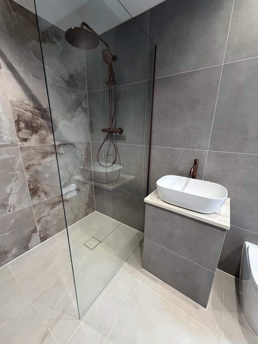 Same shower recess finished, marble-effect tiling with copper shower fittings