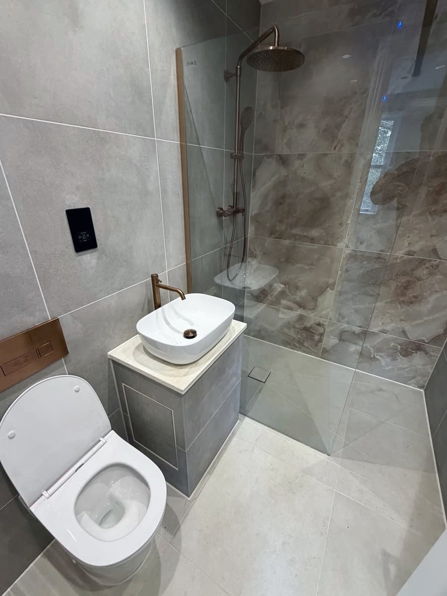 Same wet room finished, marble-effect tiling with copper fittings